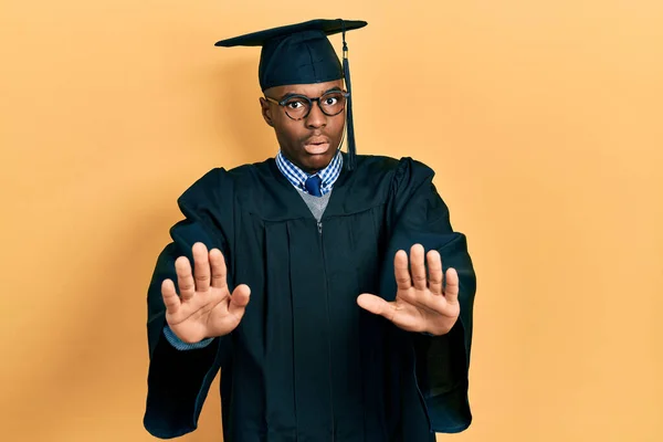 Fiatal Afro Amerikai Férfi Diplomaosztó Sapkában Szertartásköntösben Távolodó Tenyérrel Elutasítással — Stock Fotó
