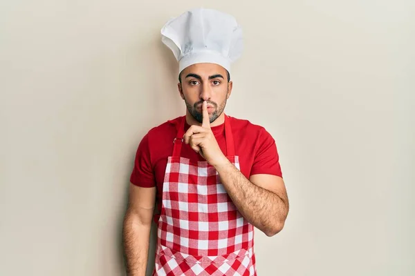 Giovane Ispanico Uniforme Panettiere Che Chiede Stare Zitto Con Dito — Foto Stock