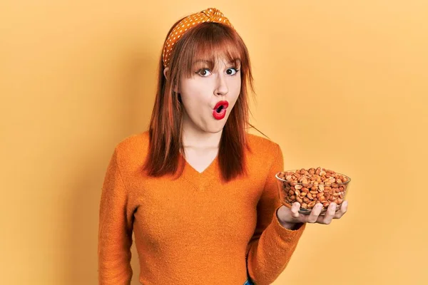 Redhead Young Woman Holding Peanuts Scared Amazed Open Mouth Surprise — Stock Photo, Image
