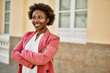 Güzel bir iş adamı Afro saçlı Amerikalı kadın şehirde mutlu ve kendinden emin bir şekilde gülümsüyor.