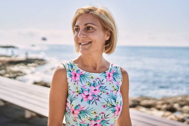 Orta yaşlı, güzel bir kadın. Deniz kenarında kendine güvenen.