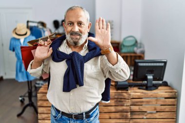 Yakışıklı son sınıf öğrencisi mağazada alışveriş poşetleri tutuyor. Merhaba diyor. Mutlu ve güler yüzlü, dostça bir jest. 