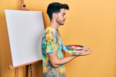 İspanyol asıllı genç bir adam paletle resim çiziyor. Yan yana duruyor, rahat profil pozu veriyor, doğal bir yüz ifadesi ve kendine güvenen bir gülümsemeyle.. 