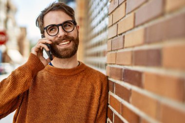 Beyaz sakallı bir adam güneşli bir günde telefonda konuşuyor.
