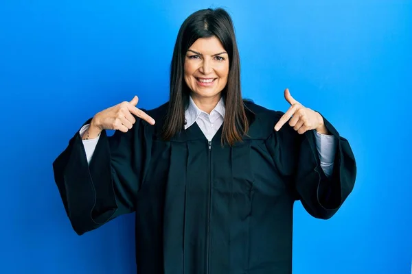 顔に笑顔で自信を持って裁判官の制服を着て若いヒスパニック系の女性 誇りと幸せ指で自分自身を指して — ストック写真