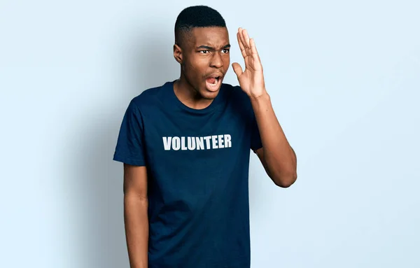 ボランティアのTシャツを着た若いアフリカ系アメリカ人男性が大声で叫び 口の上で手をつないで大声で叫んでいます コミュニケーションの概念 — ストック写真