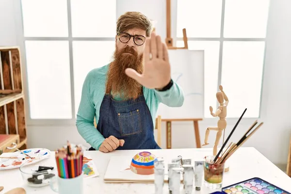 红头发男子与长胡子画粘土碗在艺术工作室做停止唱与手掌的手 用消极而严肃的手势警告人 — 图库照片