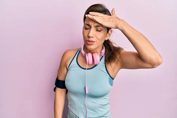 年轻的拉丁女人穿着运动服 用耳机对手头上的错误感到惊讶 记住错误 坏的记忆概念 — 图库照片