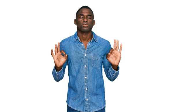カジュアルな服を着た若いアフリカ系アメリカ人の男性は 指で瞑想ジェスチャーを行う閉じて目でリラックスして笑顔 ヨガのコンセプト — ストック写真