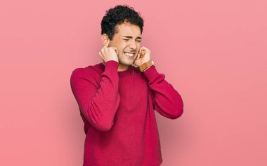 Gürültülü müzik sesi için kulaklarını parmaklarıyla kapatan sıradan kıyafetler giyen genç yakışıklı bir adam. sağır kavramı. 