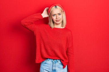 Gündelik kırmızı kazak giyen güzel sarışın kadın soru sormayı merak ediyor. Şüpheyle kararsız, kafa kafaya düşünerek. Düşünceli kavram. 