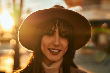 Açık havada gülümseyen, kışlık şapkalı esmer kadın.