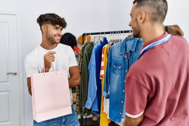 Genç İspanyol esnaf giyim mağazasında müşterilere kıyafet gösteriyor..