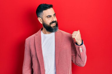 İş kıyafetleri giymiş genç İspanyol adam başparmağını yana kaldırmış, ağzı açık gülümsüyor. 