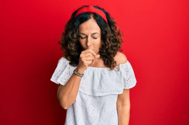 Orta yaşlı İspanyol kadın gündelik kıyafetler giyiyor kendini iyi hissetmiyor ve soğuk algınlığı veya bronşitin belirtisi olarak öksürüyor. sağlık hizmeti kavramı. 