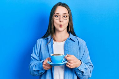 Genç İspanyol kız bir fincan kahve içiyor ağzıyla balık suratı yapıyor ve şaşı bakıyor, çılgın ve komik.. 