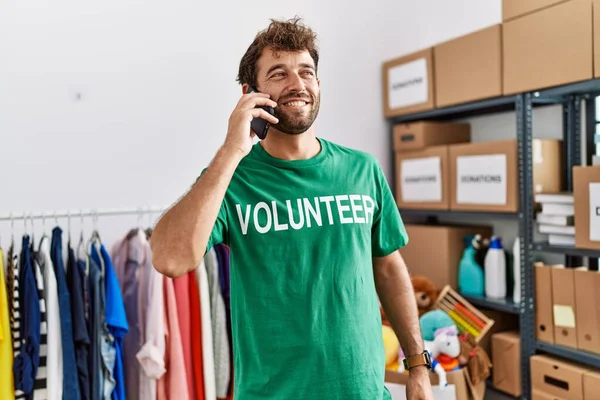 Joven Voluntario Hispano Sonriendo Feliz Hablando Teléfono Inteligente Centro Caridad —  Fotos de Stock