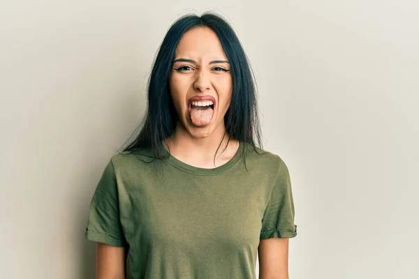 面白い表情で嬉しそうに舌を突き出しているカジュアルなTシャツを着た若いヒスパニック系の女の子 感情の概念 — ストック写真
