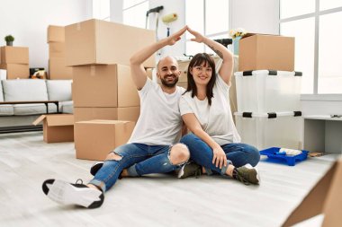 Genç İspanyol çift gülümseyerek yeni evlerinde ev sembolü yapıyor..