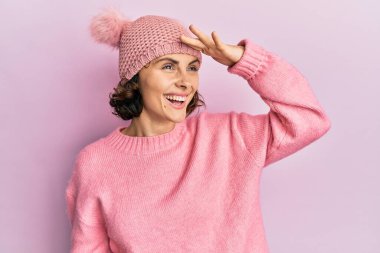 Genç esmer, sevimli yün şapkalı, mutlu ve tebessüm eden bir kadın. arama kavramı. 