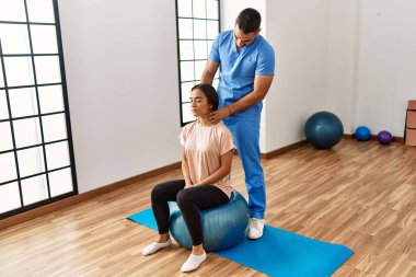 Latin erkek ve kadın fizyoterapist üniforması giyiyorlar. Rehabilitasyon merkezinde boyun masajı yapıyorlar.