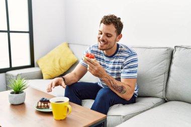 Genç İspanyol adam evde kahvaltı ederken kendine güveniyor.