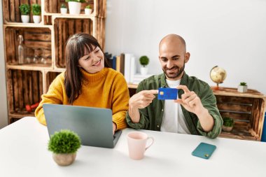 Genç İspanyol çift dizüstü bilgisayar ve kredi kartı kullanarak mutlu bir şekilde gülümsüyor..