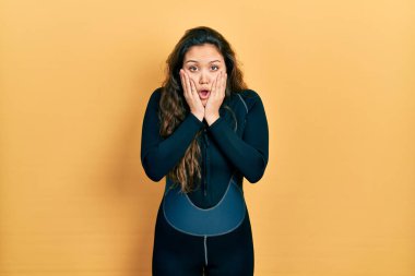 Genç İspanyol kız dalgıç neoprene üniforması giyiyor. Korkmuş ve şok olmuş. Şaşırmış ve hayrete düşmüş. 