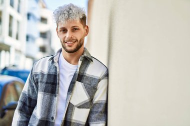 Genç İspanyol adam gülümseyerek şehirde mutlu mesut dikiliyor..