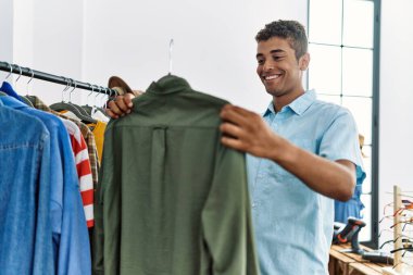 Genç İspanyol adam perakende dükkanından gömlek seçiyor.