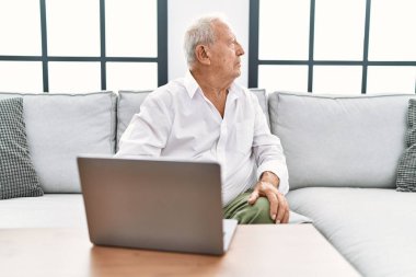 Son sınıf öğrencisi evinde dizüstü bilgisayar kullanıyor. Kanepeye oturuyor. Yan yan bakıyor, profil pozu veriyor.. 