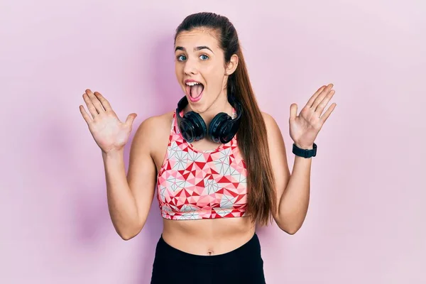 Joven Adolescente Morena Vistiendo Ropa Gimnasio Usando Auriculares Celebrando Loco —  Fotos de Stock