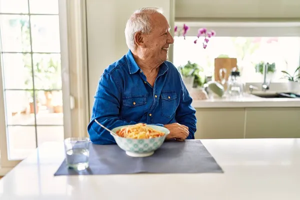 Starší Muž Šedivými Vlasy Který Doma Špagety Dívá Stranou Úsměvem — Stock fotografie
