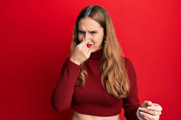 若いブロンドの女性は 鼻の上に指で息を保持し 臭いと嫌な 耐え難い匂いを嗅ぐタートルネックセーターを着ています 臭いが悪い — ストック写真