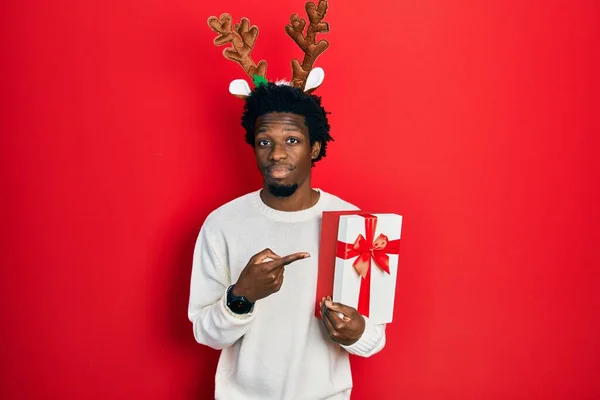 Jovem Afro Americano Vestindo Chapéu Natal Veado Segurando Presente Apontando — Fotografia de Stock