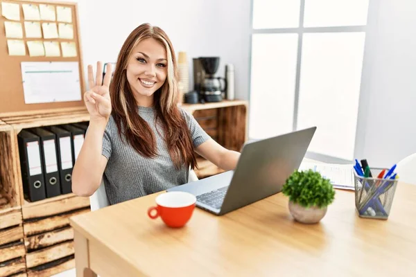 在办公室工作的年轻的黑发女人 带着笔记本电脑 用第三指尖 带着自信和快乐的笑容 — 图库照片