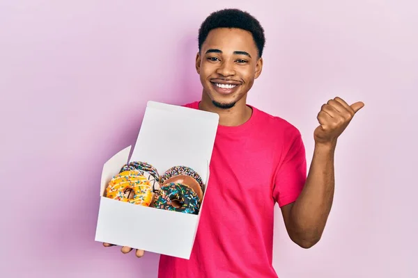 Joven Afroamericano Hombre Sosteniendo Caja Con Sabrosas Rosquillas Coloridas Apuntando —  Fotos de Stock