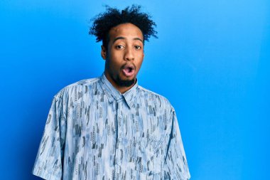 Sakallı, sıradan giyinmiş, şaşırmış, korku ve heyecan dolu bir ifadeyle şoka uğramış genç bir Afro-Amerikan.. 