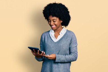 Genç Afro-Amerikalı kadın dokunmatik ped kullanıyor. Pozitif ve mutlu görünüyor. Kendine güvenen bir gülümsemeyle dişlerini gösteriyor. 