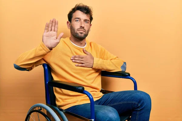 Homem Bonito Com Barba Sentado Cadeira Rodas Jurando Com Mão — Fotografia de Stock