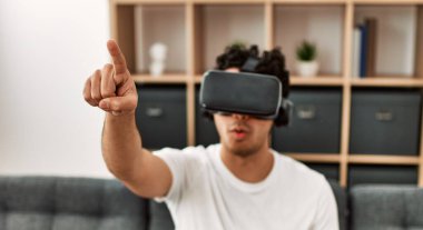 Sanal gerçeklik gözlükleriyle oynayan İspanyol genç adam evdeki kanepede oturuyor..