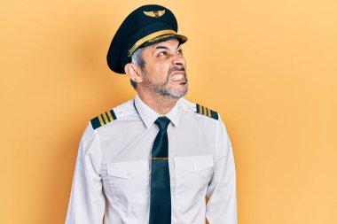 Yakışıklı, orta yaşlı, gri saçlı, uçak pilotu üniforması giyen sinirli ve kızgın bağıran sinirli ve öfkeliydi. Öfkeyle bağırıyordu. öfke ve agresif konsept. 