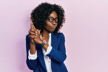 Young african american woman wearing business clothes and glasses holding symbolic gun with hand gesture, playing killing shooting weapons, angry face 