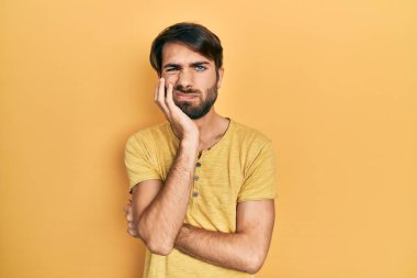 Günlük kıyafetler giyen genç İspanyol adam kollarını kavuşturarak depresyondan sıkılmış ve yorgun görünüyor.. 