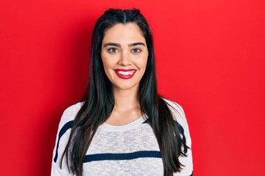 Yüzünde mutlu ve havalı bir gülümseme olan günlük kıyafetler giyen genç İspanyol kız. şanslı kişi. 