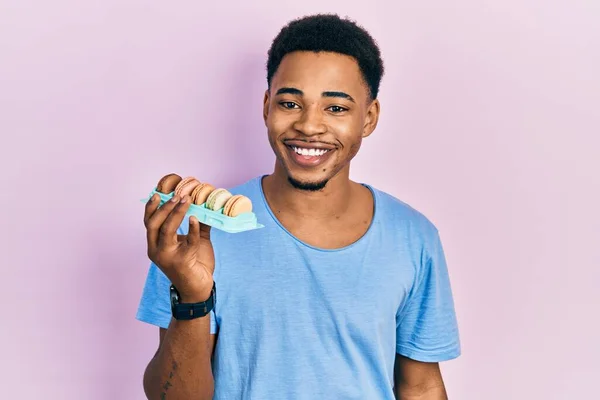 Young African American Man Holding Macarons Looking Positive Happy Standing — Stockfoto