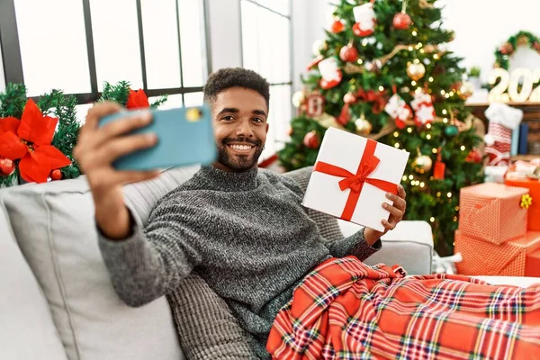Młody Afroamerykanin Człowiek Selfie Przez Smartfon Gospodarstwa Prezent Świąteczny Domu — Zdjęcie stockowe