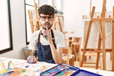 Sanat stüdyosunda sakallı İspanyol bir adam parmakları dudaklarında sessiz olmak istiyor. sessizlik ve gizli konsept. 