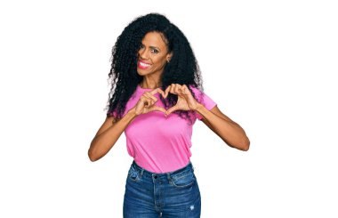 Orta yaşlı Afro-Amerikan kadın, günlük giysiler giyip, aşkla gülümsüyor. Elleriyle kalp sembolü ve şekli gösteriyor. romantik kavram. 