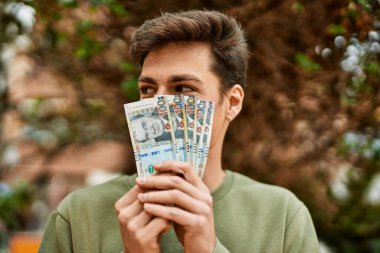 Genç İspanyol adam gülümsüyor Peru tabanlı banknotlarla yüzünü kapatıyor..